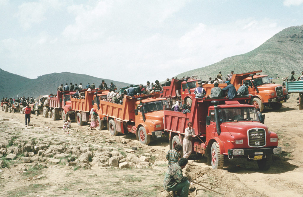 Kurdish refugees travel by truck between their mountain campsites and tent